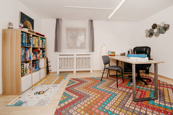 Praxisraum mit Schreibtisch und Bücherregal