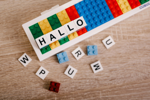 Bunte Spielsteine und Buchstabensteine mit dem Wort "Hallo"