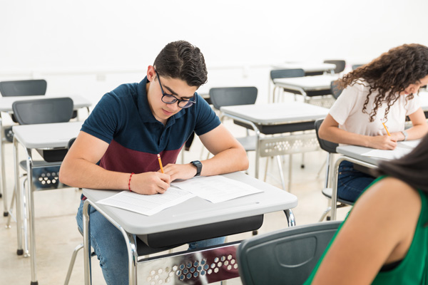 3 Jugendliche sitzen bei einer Prüfungsarbeit in einem Klassenzimmer