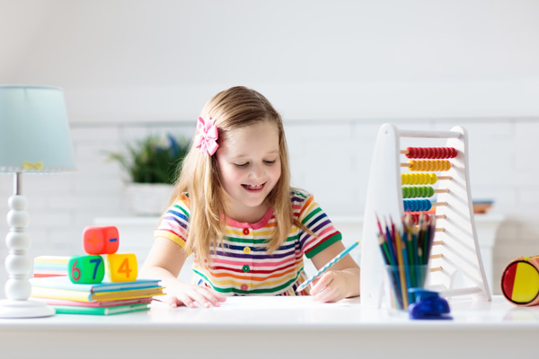 Mädchen schreibt etwas auf und sitzt am Schreibtisch