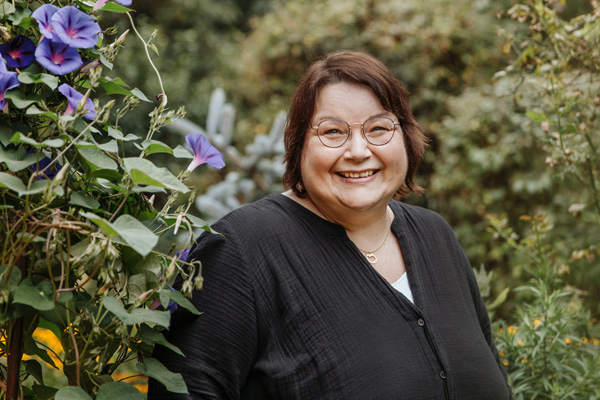 Michaela Zieglmeier steht bei Pflanzen und lächelt in die Kamera